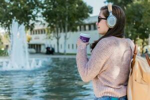 jong vrouw drinken koffie in een stad park gedurende een zonnig herfst middag. foto