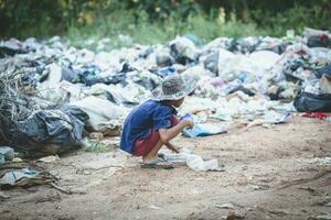 een arm jongen verzamelen vuilnis verspilling van een stortplaats plaats. concept van levensonderhoud van arm kinderen kind arbeid. kind arbeid, menselijk mensenhandel, armoede concept foto