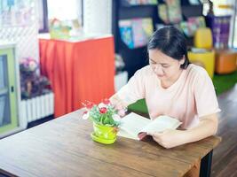 vrouw aan het studeren in de bibliotheek dat vol van boeken. opvatting van onderwijs.in modern interieur bibliotheek van Universiteit kiezen boek tussen boekenkasten Bij bibliotheek. zittend Aan de tafel lezing een boek foto