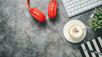 top visie, donker kantoor bureau met toetsenbord computer, kop van koffie, pen, koptelefoon en notitieboekje, kopiëren ruimte, bespotten omhoog.. foto