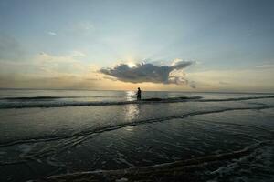 de schoonheid van de zonsondergang Aan de strand met de silhouet van een visser foto