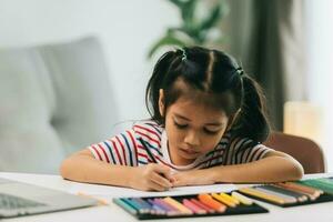 selectief focus van schattig Aziatisch kind tekening met kleur potloden Bij huis foto