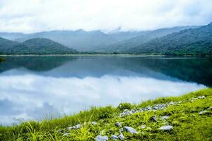 mooi landschap met bergen dramatisch meer in de mist reflectie van lucht en wolk in water foto