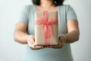 vrouw draag- geschenk papier doos stropdas schattig lint voor speciaal gelegenheid. levering Bezig met verzenden Cadeau naar iemand speciaal naar dank of verrassing. foto