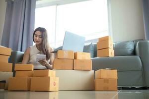 vrouw controle pakket van goederen van klant online bestellen is alleen in haar huis kantoor net zo ze is een mkb ondernemer en toepassingen haar telefoon en tablet naar markt online. concept online verkoop bedrijf foto