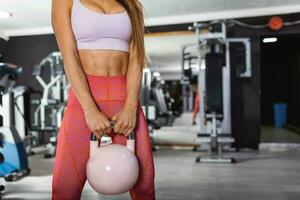 aantrekkelijk jong atleet met gespierd lichaam oefenen crossfit. vrouw in sportkleding aan het doen crossfit training met waterkoker klok foto