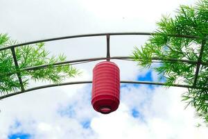een rood Japans lantaarn, of chochin, is hing Aan een bamboe boog. het is een symbool van drinken en aan het eten, zo het is populair naar hangen in voorkant van winkels en restaurants en schrijven berichten uitnodigend klanten. foto