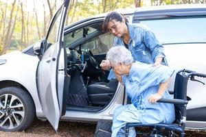 hulp en ondersteuning aziatische senior of oudere oude dame vrouw patiënt zittend op rolstoel voorbereiden om naar haar auto te gaan, gezond sterk medisch concept. foto