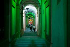 Bologna, Italië- juni 23, 2023-mensen wandeling Bij nacht onder de arcades leidend naar de heiligdom van san luca verlichte voor de eerste editie van de bologna arcades festival. foto