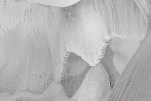 witte reliëfmuren van ijs en sneeuw in een grot. abstracte gestructureerde natuurlijke achtergrond. foto