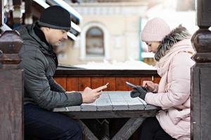 een stel wacht op hun bestelling voor de lunch in een straatcafé, sms'en via de telefoon. communicatie met mensen op een smartphone.