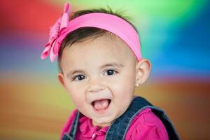 portret van een gelukkig mooi tien maanden baby meisje Aan een kleurrijk achtergrond. vroeg stimulatie voor peuters concept. foto