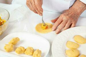 voorbereiding van de traditioneel pasteitjes van de regio van cauca in Colombia, gebeld empanadas de pipiaan - senior vrouw vulling de pasteitjes foto