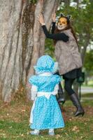 weinig meisje Aan grootmoeder kostuum spelen met haar mama. echt familie hebben pret terwijl gebruik makend van kostuums van de weinig rood rijden kap verhaal in halloween. foto