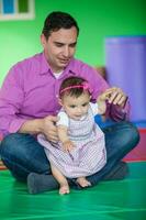 mooi tien maanden baby meisje spelen met haar pa. vroeg stimulatie voor peuters concept. foto