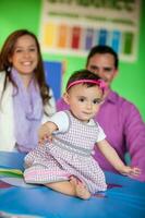 mooi tien maanden baby meisje spelen met haar ouders Aan achtergrond. vroeg stimulatie voor peuters concept. foto