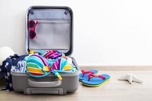 kleurrijke bikini en kleding in bagage op de laminaatvloer
