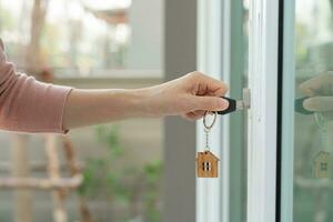 landheer sleutel voor ontgrendelen huis is aangesloten in de deur. tweede hand- huis voor huur en uitverkoop. sleutelhanger is blazen in de wind. hypotheek voor nieuw huis, kopen, verkopen, renoveren, investering, baasje, landgoed foto