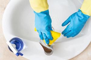 handen met handschoenen die een badkamer schoonmaken met een gele doek. desinfectie of hygiëne concept foto