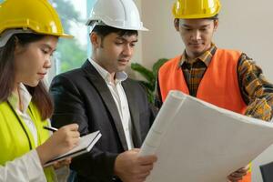 ingenieurs team en eigenaar bespreken controleren en recensie de blauwdruk van bouw. aannemer inspectie tekening voordat begin project civiel. project planning, overleg plegen, architectuur. foto