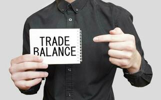 zakenman Holding een wit kladblok met tekst handel evenwicht, bedrijf concept foto