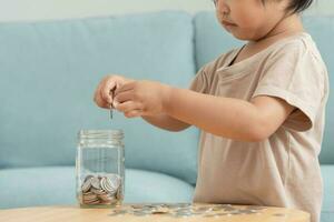 opslaan geld. kinderen zetten munt voor besparing. rijkdom, financiën, verzekering, investering, opleiding, toekomst, plan leven, leren, bankieren, familie, Gezondheid, Gezondheid en ongeluk verzekering. foto