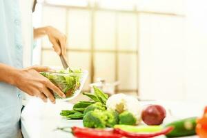 jong vrouw in de huis keuken bereidt zich voor een oprecht salade met vers groenten foto