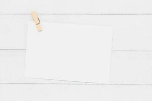 wit papier kaart met houten klem Aan wit tafel achtergrond voor bruiloft uitnodiging kaart ontwerp en schrijven of het drukken Aan. foto