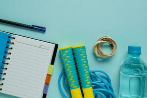 notebooks met meten plakband, vers drinken water, springen touw Aan blauw achtergrond foto