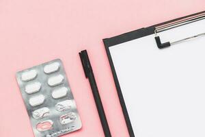 klembord met papier, zwart pen en blaar pak van geneeskunde pil Aan roze achtergrond voor medisch en gezondheidszorg concept foto