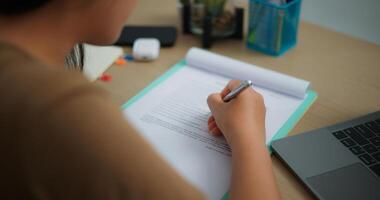 oung Aziatisch vrouw werken met een laptop en schrijven Aan papier Aan een bureau foto