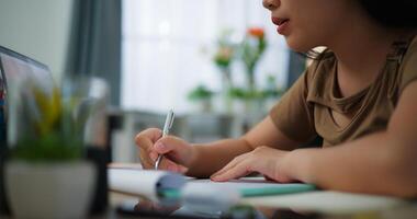 oung Aziatisch vrouw werken met een laptop en schrijven Aan papier Aan een bureau foto