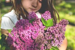 klein meisje met boeket lila in haar handen foto