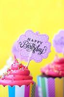 smakelijke aardbei cupcakes met gelukkige verjaardag wenskaart op gele achtergrond. feest achtergrond