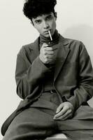 Mens en leerling portret wit echt mode zittend zwart attent hipster roken sigaret foto
