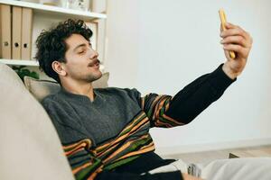 Mens communicatie levensstijl bericht sofa telefoon typen huis technologie selfie vrije tijd foto