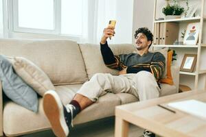 Holding Mens bericht huis sofa typen communicatie technologie selfie kamer wit levensstijl telefoon zelfverzekerd foto