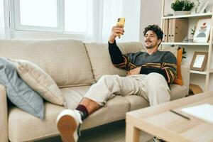 Mens sofa selfie huis telefoon levensstijl bericht kamer typen communicatie leven technologie foto