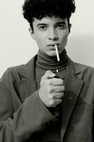 Mens mode zwart zittend wit roken en sigaret portret foto