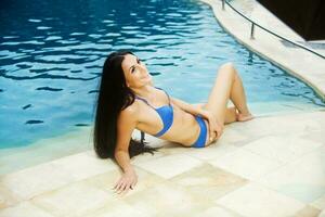 mooi brunette vrouw door de zwemmen zwembad foto