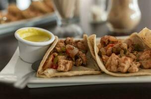 heerlijk Mexicaans kip taco's met salsa en pico de gallo geserveerd Aan de tafel, visie van kip taco's geserveerd Aan de tafel. detailopname van Mexicaans kip taco's geserveerd foto