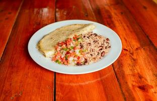 galopperen schotel met quesillo en pico de gallo Aan houten tafel. traditioneel gallo pinto maaltijd met pico de gallo en quesillo geserveerd foto