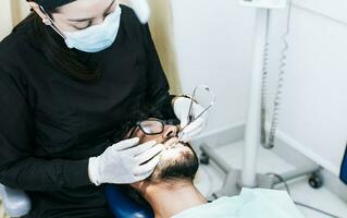 tandarts controle een beugel naar geduldig, geduldig gecontroleerd door tandarts, tandarts het uitvoeren van tandheelkundig controle foto
