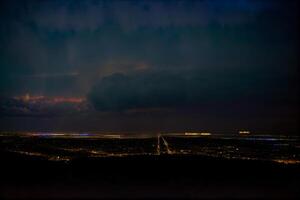 een visie van een stad Bij nacht van de top van een heuvel. ai gegenereerd foto