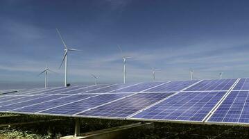 zonne- panelen met wind turbines tegen blauw lucht achtergrond. fotovoltaïsch, alternatief elektriciteit bron. duurzame middelen concept. foto