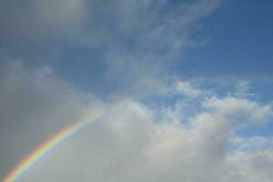 de wolken zijn dun, maar de regen creëert een regenboog aan de overkant de horizon. foto