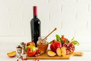 een reeks van traditioneel voedsel en een fles van rood wijn voor Rosh hashanah tegen de backdrop van een wit steen muur. voorkant visie. Joods nieuw jaar. foto