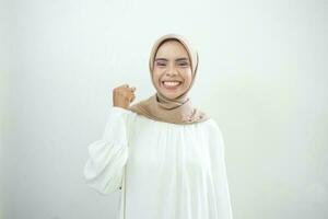 opgewonden Aziatisch moslim vrouw vieren zege geïsoleerd over- wit achtergrond foto