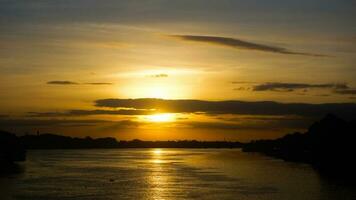 mooi zonsopkomst over- boom in een zomer ochtend- en de rivier- of meer en wolken weerspiegeld in kalmte water. foto