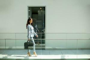 mooi jong bedrijf vrouw wandelen met aktentas in de kantoor gang foto